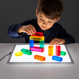 Child exploring translucent blocks on an A4 light panel